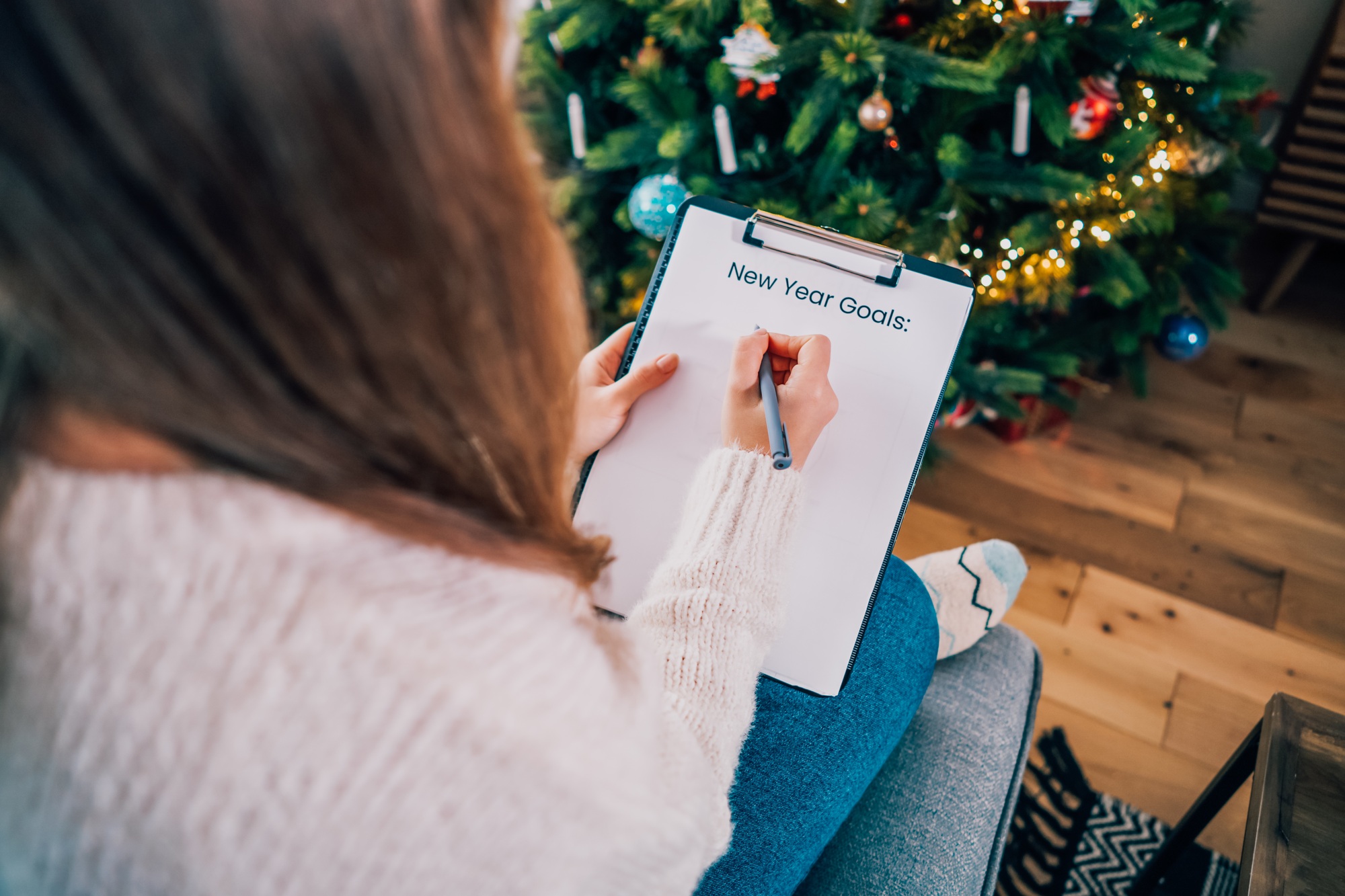 Woman hand writing New year's goals on note paper in new year day. New year resolutions list,